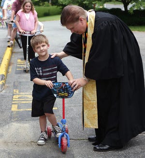 Andrew Pinner of Hudson gets his Spider-man scooter blessed by the Rev. Jay Mulligan, pastor of the First Federal Church, in Hudson.
