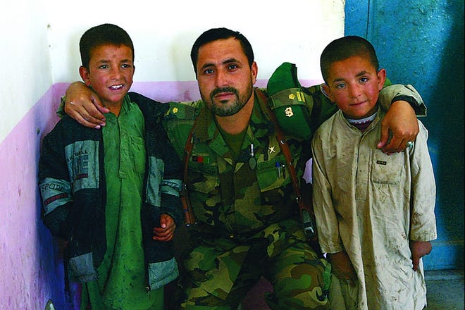 A Soldier of the Afghan National Army poses for a photo with an Afghan boy Juma Gul, 6, a defused suicide bomber, left, and his brother Dad Gul at a joint US-Afghan military command center in Andar district of Ghazni province, west of Kabul, Afghanistan on Saturday, June 23, 2007. (AP Photo/Musadeq Sadeq)