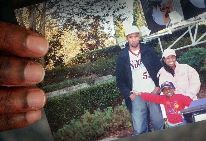 A family friend holds a snapshot of John Lubin, 24, with a younger brother and sister. Randolph had its second homicide in a week when Lubin was shot and killed at a house party on Bayberry Lane.