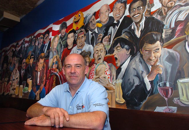 In the mural behind him, Jay Ellis, owner of The Chicken Bone Saloon in Framingham, is portrayed next to Dean Martin.
