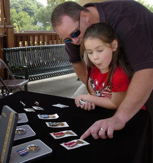 Matt LaRose explains the medals awarded to his grandfather, the late WWII veteran Ralph Grenon, to his daughter, Kylie, 5.