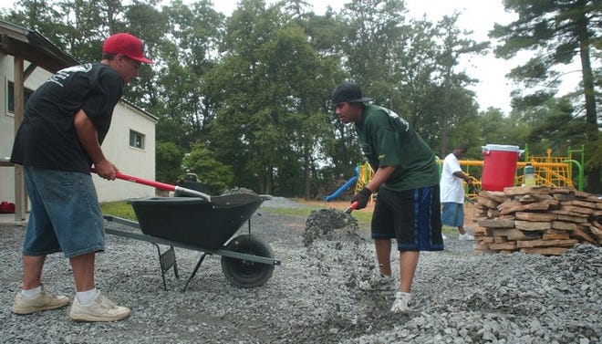 From left: John Cassidy, 15, of East Stroudsburg and Niko Tilley, 17, of Stroudsburg shovel stone into a wheelbarrow while they work in the playground facility at the Beacon School in Shawnee on Wednesday morning.