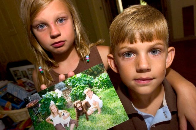 Reagan Albright, 10, and brother Ryan, 7, hold a picture of themselves with their missing chocolate Labrador retriever, Toby. Top, Clay Albright raises the reward to $1,000 for Toby's return.