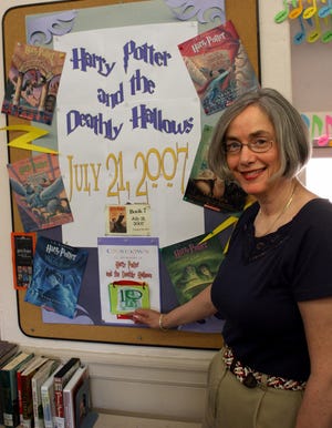 Librarian Denise Kofron in front of the poster that counts down the day to the new Harry Potter book at the Hopkinton Public Library.