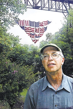 Steve Ladin stands in front of his 80-foot-by-40-foot American flag banner hanging off the Rosendale railroad bridge in Rosendale.