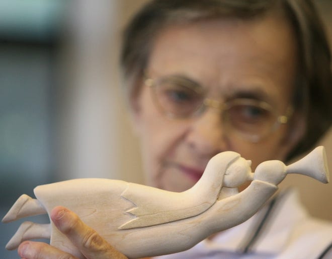 Evelyn Knight holds up an angel that she is working on as part of a wood-carving group that meets at Dunnellon Square Mobile Home Park clubhouse. Below, a "wood spirit" is seen carved into a pencil at the wood-carving group's meeting.
