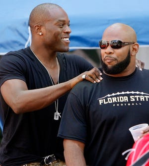 Tampa Bay Buccaneers' Greg Spires, right, gets a pat on the back from Simeon Rice as they report to training camp on Thursday in Celebration. Rice was later cut by the Bucs.