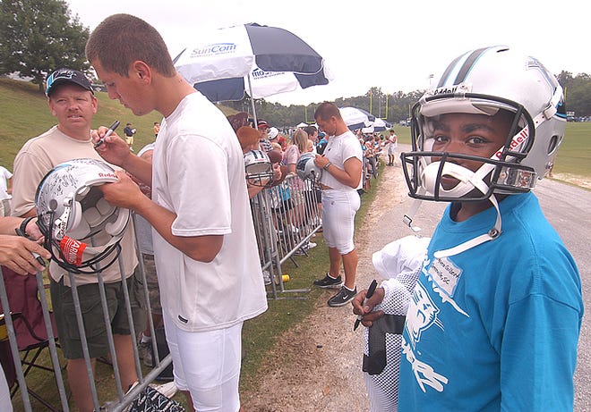 Jaquea Gibert, 13, right, with the Boys & Girls Club, carries the jersey and helmet for Carolina Panthers' Andrew Wellock, left, as he signs autographs for fans after the football practice at Wofford College in Spartanburg Monday morning.