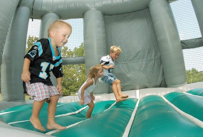 At the Panthers Experience in Spartanburg, from left, Dorn Stoliker, 3, Cora Stoliker, 6, and Maxwell Green, 5, jump around in the moon bounce. The activities keep little ones entertained while the grown-ups watch Panther practice.