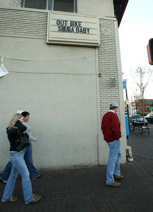 Pedestrians walk by the building on the Strip in Tuscaloosa that used to house the Booth bar in December.