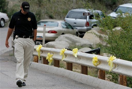 Emery County Sheriff Sgt. Dusty Butler looks down as he walks past six yellow ribbons at the entrance to the Crandall Canyon Mine Friday in northwest of Huntington, Utah. The desperate underground drive to reach six trapped miners will be suspended indefinitely after a catastrophic cave-in killed three rescuers inside a mountainside mine, a federal official said Friday.