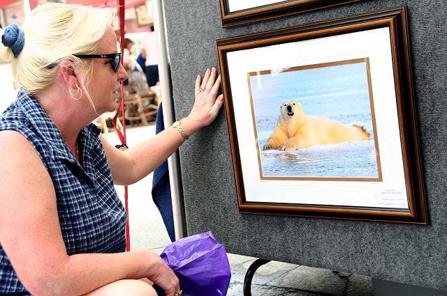 Mike Colclough/For The Citizen
 A PHOTO OF A POLAR BEAR provides a special attraction to Diane York of Laconia during Saturday's extreme heat. The photograph, taken by Mark Klein of Mirror Lake, was among the items on display at the Meredith Fine Arts and Crafts Festival. Klein photographed the bear while on a photography trip to Churchill, Manitoba, which is a haven for the bears during the late fall.