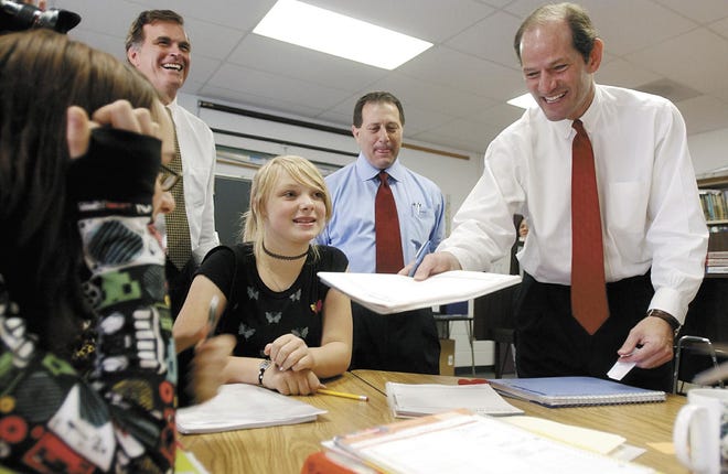 They felt they had a valid excuse – a visit with New York State Governor Eliot Spitzer – for being late for class, but eighth-graders Emma Franci (left) and Jackie Lehmann weren't taking any chances. They asked Spitzer to sign their late excuses, or "passes," when he stopped by their classroom at West Irondequoit's Dake School during his about hour-long trip to the district Thursday morning. In the background are district Superintendent Jeff Crane (left) and state Assemblyman Joe Morelle.