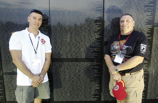 Richard Poness Jr. of Gates and his father, Ronald Poness, Sr. of Gates stand in front of the Dignity Vietnam Memorial Wall at Gates Memorial Park.