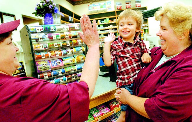 Penny Eider, bakery manager for the Big M in Clifton Springs, high-fives 3-year-old Kiernan Bolan — in the arms of deli worker Mary Mattoon — after correctly reading numbers off a lottery ticket dispenser.