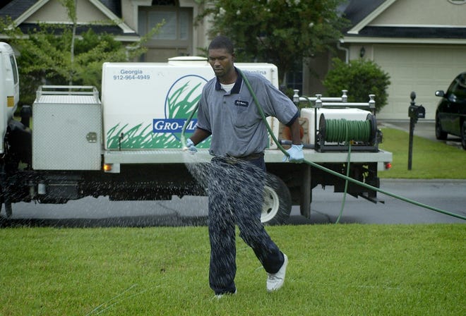 Ricardo Davis, working for Gro-Master, fertilizes a lawn in Pooler.