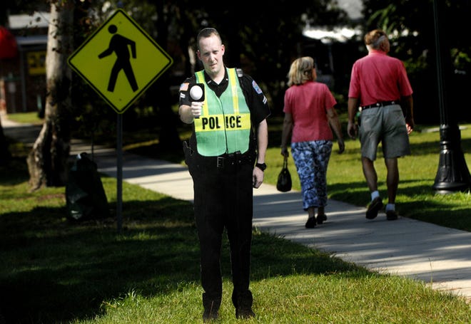 A couple of pedestrians walk past a cardboard cutout of a police officer in front of Trinity Lutheran Home on Laurens Street in Aiken. The cardboard cop was placed next to a parked patrol car in hopes of deterring motorists from speeding.