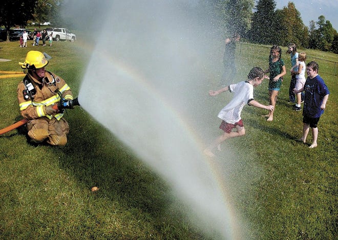 Rush Firefighter Warner Wandersleben sprays water from a hose and allows children to run through the water during the annual Rush Fall Fest Saturday, Sept. 22. The fest featured numerous events, including pie-eating contests and bake-offs.