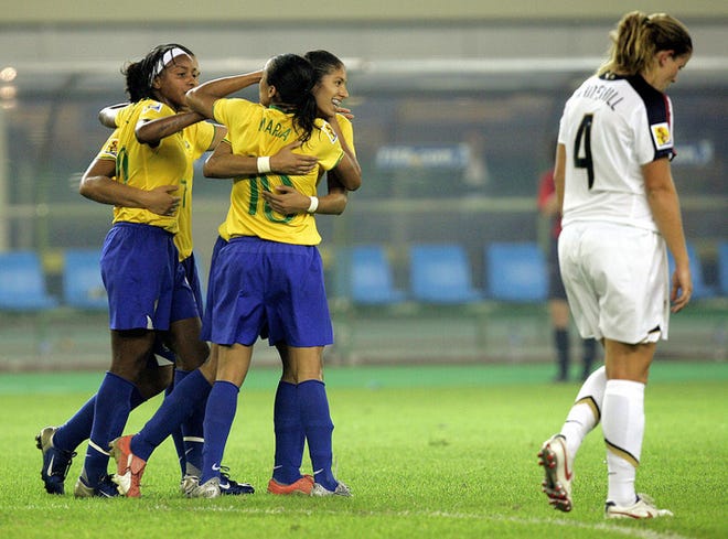 Brazil's Marta (10) celebrates with teammates their 4-0 victory over the United States in the Women's World Cup semifinals in Hangzhou, China as dejected defender Cat Whitehill walks away. Brazil will play Germany in Sunday's final in Shanghai.