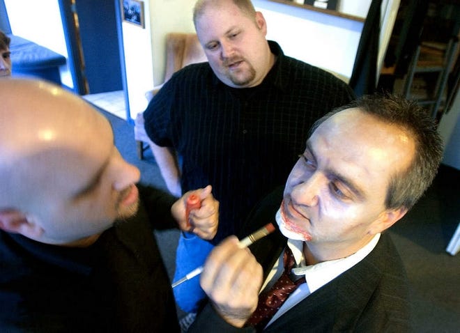 Jeremy Woloski, center, watches as make-up artist Robert Latino, left, transforms cast member Fred D'Angelo's face into that of a zombie, prior to a dress rehearsal at the Stageloft Theater.