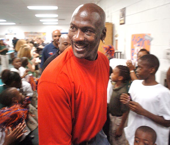 Basketball legend and Wilmington native Michael Jordan is greeted by area children at the Community Boys & Girls Club as he dedicates a new Charlotte Bobcats themed reading room in the center. Jordan, the Managing Member of Basketball Operations for the Bobcats, is in town as the team holds their annual preseason practice at Trask Coliseum. The reading room, one of six the Bobcats have opened across the state, is stocked with books and educational materials for the Boys & Girls Club to supplement their activities.