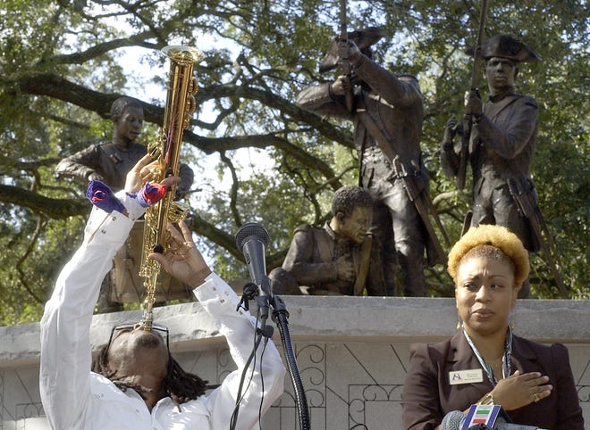 Saxophonist Jowee Omicil plays the national anthems of the United States and Haiti at the start of the unveiling of the Haitian Memorial Monument in Franklin Square. Observing is Bernice Fidelia, Haitian-American Historical Society board member and Master of Ceremonies of the event.