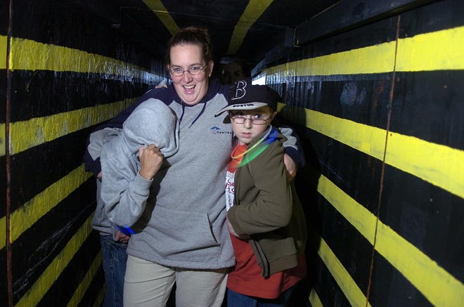 Kerrie Gawrys of Stoughton, center, her son Thomas, right, and family friend Justin McCarthy of Stoughton are scared as they walk through the maze at the Lakeville Haunted Woods.