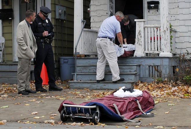 Coroners remove the body of a victim from the upstairs apartment after a shooting Thursday at 942-944 Stark St. in West Utica. Two people are dead after three people were shot late this morning, officials said.