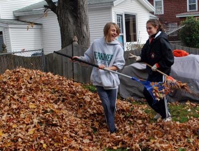 Mohawk High School tenth-grade students Ashley Bunce and Christy Traglia share a laugh as they rake leaves on Saturday at a home on Colombia Street in Mohawk.