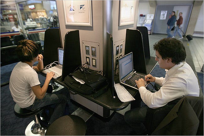Travelers use their laptops at a power station in the Dallas-Fort Worth International Airport.