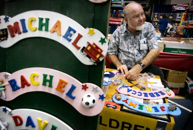 Bill Middleton of Children's Room Signs in Palm Bay reacts to customers as he builds a personalized children's bedroom sign during the annual Holiday Craft Festival at the Stephen C. O'Connell Center on Saturday.
