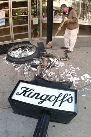 Ronald Oswandel sweeps up glass from the Kingoff's Jewelers clock, which was destroyed early Thursday by a truck.
