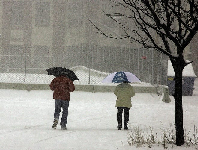 Umbrellas help ward off heavy snow for two people walking past the Boys' Club on Court Street in Taunton Thursday.