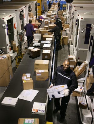 FedEx drivers pick packages from a conveyor belt for their delivery routes on Thursday.