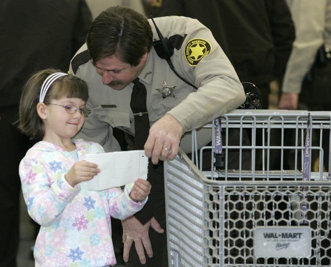 Boone County Sheriff Deputy Keith Clark and Haylee Gibbs, 5, of Poplar Grove look over Gibbs' Christmas list before they go shopping Dec. 15, 2007, at Wal-Mart in Belvidere.
