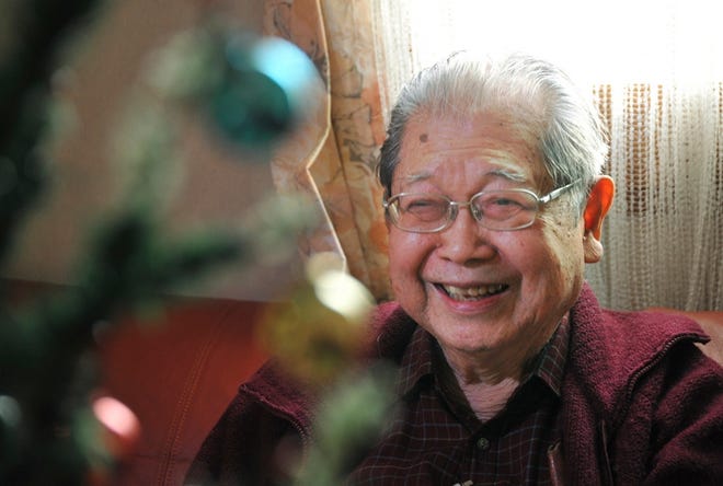 Warren Nobuaki Iwatake smiles while sitting by a Christmas tree that was purchased by his father. His family has put up for 70 years.
