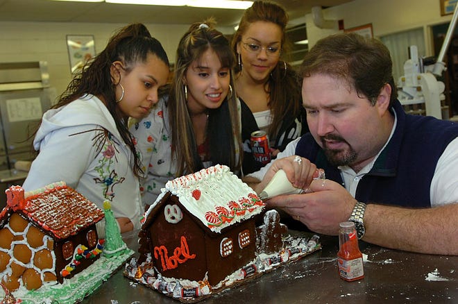 Assabet Valley students Julie DePaz, left, Jessica Lopes and Kelly Gordon get a little help on the their gingerbread house from business teacher and gingerbread house expert Joe Dalton.