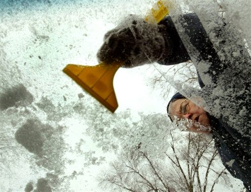 Lois Hinrichsen removes an ice and snow mixture from her windshield in Davenport, Iowa Sunday Dec. 23, 2007. Highways were hazardous for holiday travelers Sunday and thousands of homes and businesses had no electricity in the Midwest as a storm blew through the region with heavy snow and howling wind.