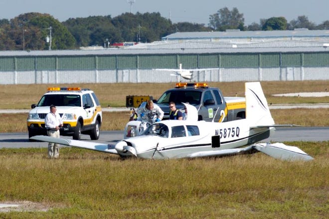 Investigators examine the wreckage of a single-engine Mooney next to a runway at Sarasota-Bradenton International Airport on Wednesday afternoon. The plane's engine sputtered after taking off according to witnesses, and the pilot quickly lowered the landing gear and banked hard to the left in an effort to return to the runway. The plane hit the ground and cartwheeled to a stop in the grassy area just off the runway. The pilot walked away from the plane and sat down after the crash.