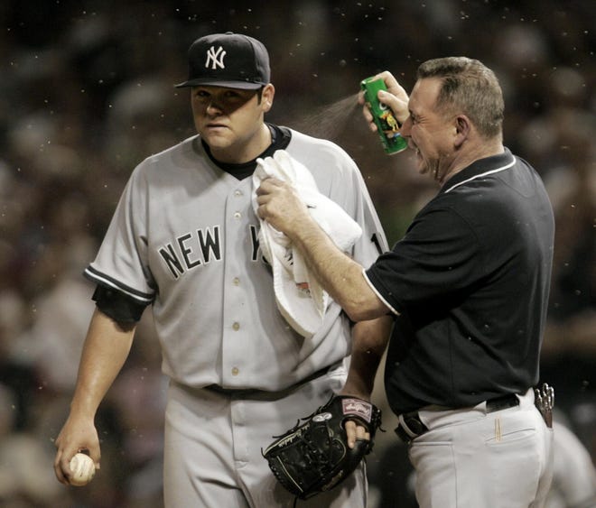 New York Yankees head trainer Gene Monahan sprays pitcher Joba Chamberlain with bug spray as swarms of small insects swarm during an American League Division Series baseball game Oct. 5 against the Cleveland Indians in Cleveland.