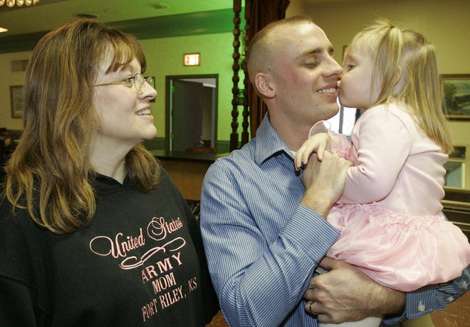 Cadence Tryggestad, 2, gives her dad, Sgt. Justin Tryggestad, a big kiss at a surprise party for Tryggestad on Dec. 30, 2007, at the Svithiod Hall in Rockford. Watching is Justin's mom, Dawn. Cadence didn't care for the idea of giving her dad a kiss in front of a crowd, but the promise of candy did the trick.