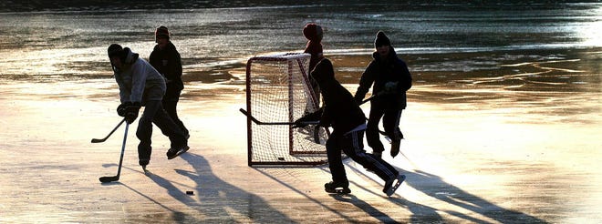 Children play hockey on a frozen cranberry bog off Oak Street in Duxbury after school on Thursday.