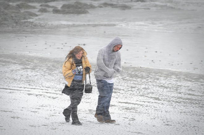 Dominick Tebaldi, right, and Laura Portier, both of Sunderland, walk in the windswept snow on Gunrock Beach in Hull on Monday.