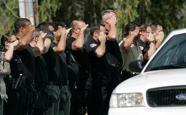 Miami area police officers honor Detective James Walker as his body is taken away, Tuesday, Jan. 8, 2008 from the North Miami Beach, Fla. crime scene where he was found shot to death. Walker is the fourth police officer killed in south Florida in recent months. Walker's body was taken away in a police caravan.