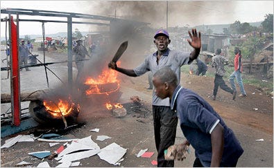 Men armed with machetes and rocks at a makeshift roadblock in Kisumu, Kenya, where rioters rampaged Monday, apparently in revenge for the killing of 19 people in a house fire on Sunday.