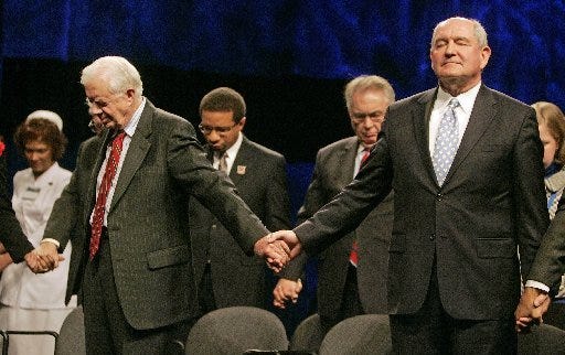 Former President Jimmy Carter, left, and Georgia Gov. Sonny Perdue pray during the opening session of the New Baptist Covenant in Atlanta on Wednesday.