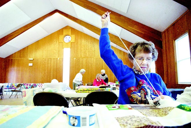 Quilter Doris Fosberg of Gates uses yarn to make ties on the quilt's fabric during Saturday morning's workshop at the United Methodist Church of North Chili. She says she enjoys the fellowship among the group of quilters.