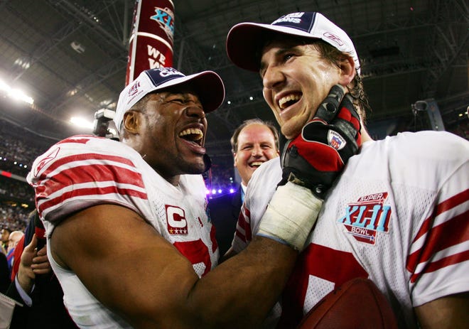 GLENDALE, AZ - FEBRUARY 03: Quarterback Eli Manning #10 of the New York Giants celebrates with teammate Michael Strahan #92 after defeating the New England Patriots 17-14 during Super Bowl XLII on February 3, 2008 at the University of Phoenix Stadium in Glendale, Arizona. (Photo by Harry How/Getty Images)