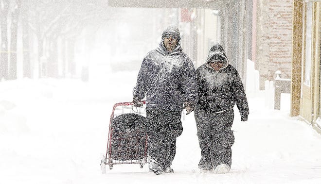 Monsy Colon and Generosa Canales of Monticello make their way home from shopping yesterday on Broadway in Monticello, as the wet snow sticks to their clothes.