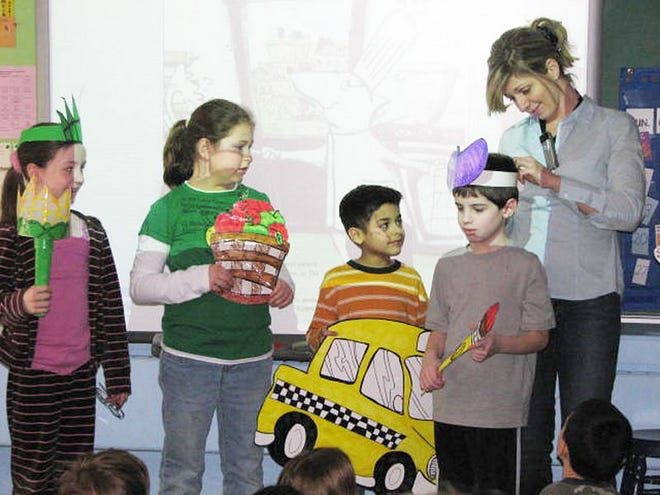 Scotchtown Avenue Elementary School students represent the cities of New York and Paris. From left, Victoria Schmidt represents the Statue of Liberty, Reaghan Duval holds a basket of apples, Matthew Ortiz shows off his yellow taxi cab, and author and illustrator Marie LeTourneau helps Michael Ehling dress up as a Parisian painter.